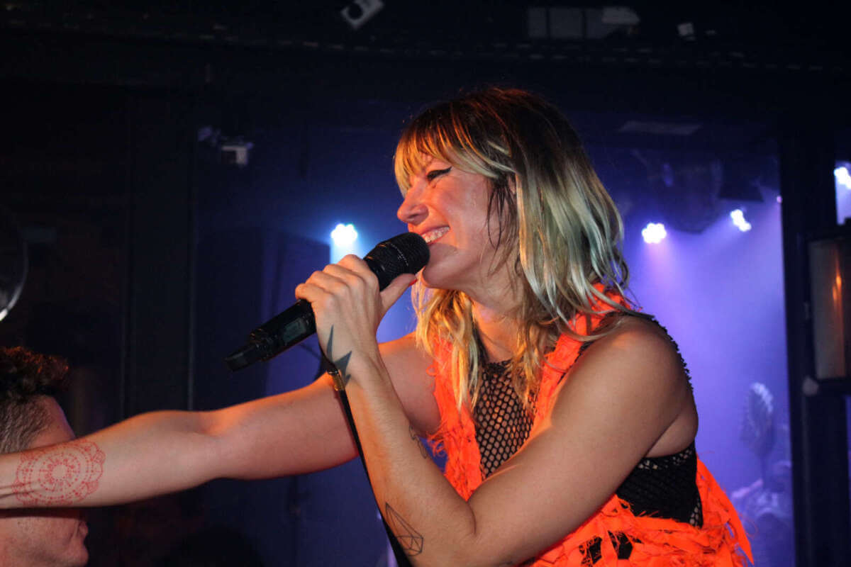 Energiegeladen und nah dran am Publikum: Die Sängerin der Band MIA. performt mit Mikrofon in der Hand auf der Bühne und strahlt dabei pure Spielfreude aus. In dynamischer Pose, umgeben von farbigem Bühnenlicht, entsteht ein intensiver Live-Moment – genau die Art von Konzertgefühl, die „Sommer im Park 2026“ in Vellmar verspricht. MiA. 2015 im Theaterstübchen in Kassel | (c) Wildwechsel