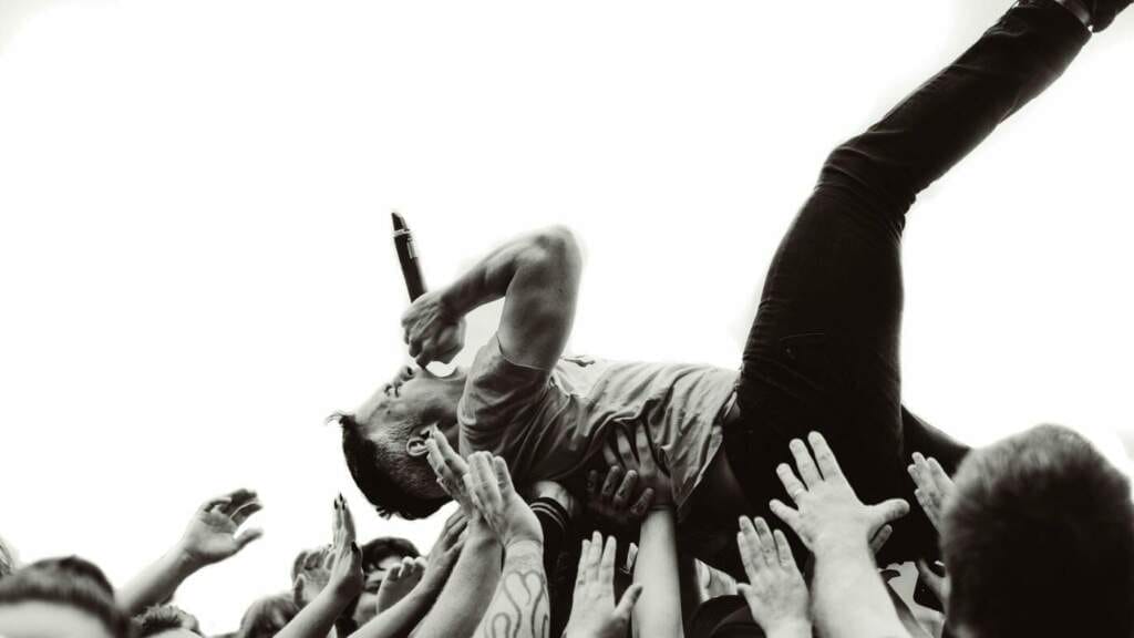 Sänger stagedivet mit Mikrofon über Festivalpublikum Wenn die Band auf der Bühne so richtig abgeht, ist die Steigerung davon meist nur noch das sogenannte Stagediving. Bei jedem echten Festival- oder Openair-Konzert kann man eigentlich früher oder später, mit so einer Showeinlage rechnen. Und oftmals, sind auch Zuschauer mit dabei beim Bühnen-Tauchen! Wer sich dabei verletzt, findet in unserer Festival-Checkliste auch dafür ein paar Tipps! | (c) Christian West auf Pixabay (c) Christian West auf Pixabay | Festival-Tipps und Festival-Packliste: Alles für das nächste Festival!