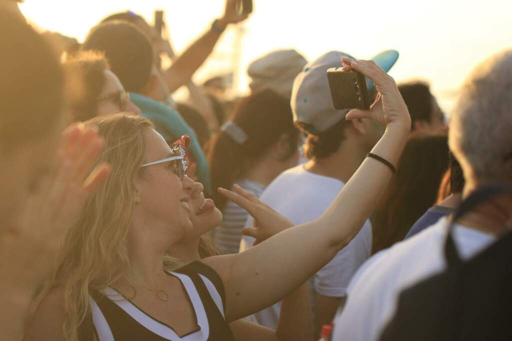 Zwei Frauen machen Selfie beim Festival in der Abendsonne Die weiblichen Besucher eines Festivals oder Openairs haben oftmals ganz andere Prioritäten auf ihrer Festival-Packliste. Unser ist individuell einsetztbar. | (c) Orna Wachman auf Pixabay