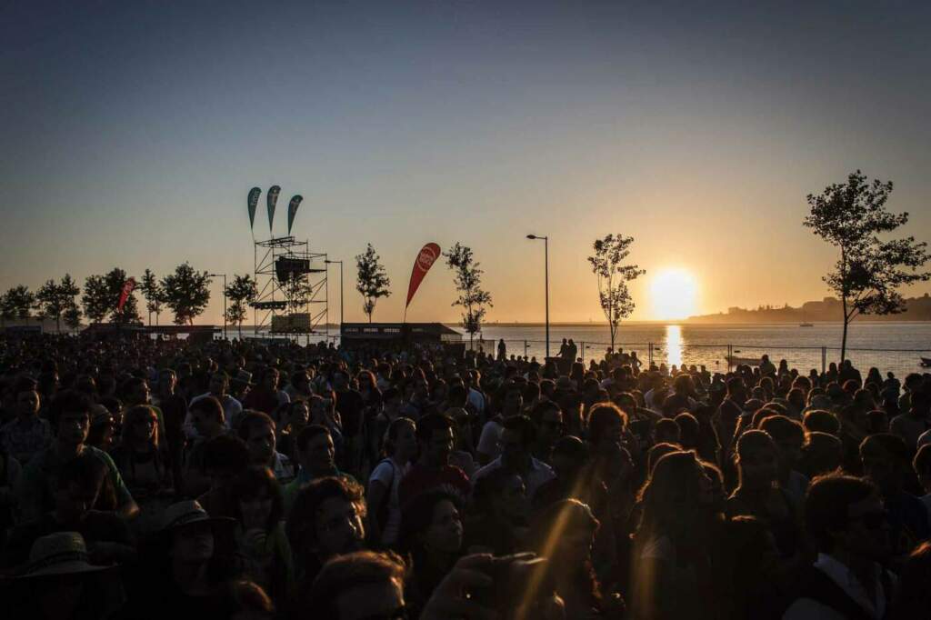 Festivalbesucher bei Sonnenuntergang am Wasser versammelt Die Stimmung unter den Besuchern ist auf einem Festival immer ganz besonders! Hier findest Du zudem jede Menge Tipps für die optimale Festival-Packliste. Kannst die online ausfüllen und downloaden und ausdrucken! | (c) Rui Neves auf Pixabay