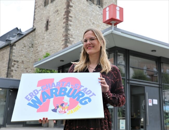 10 Jahre Erd-Charta-Stadt Warburg: Valeria Geritzen, Koordinatorin und Sprecherin der Erd-Charta Ideenwerkstatt Warburg, mit dem Logo auf dem Warburger Neustadtmarktplatz. | (c) Ideenwerkstatt/Simone Flörke