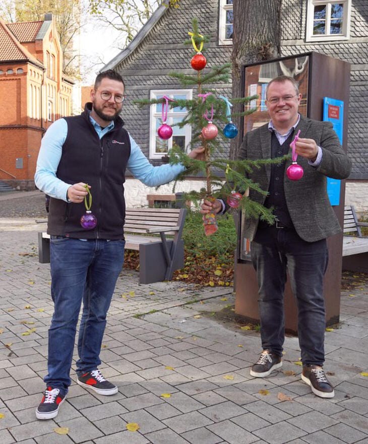 Organisatoren des Nikolausmarkts in Brakel schmücken Weihnachtsbaum mit bunten Kugeln Marktmeister Benedikt Gönnewicht und Bernhard Fischer, Vorstandsmitglied des Werberings Brakel, stellen die Idee des Plünderbaums vor | (c) Stadt Brakel