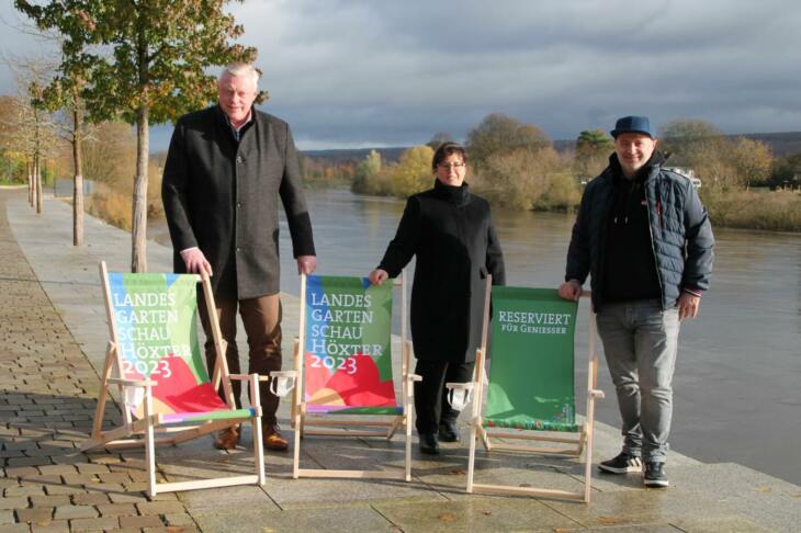Weserscholle Events, Höxter, Konzerte Auch 2024 ist auf der Weserscholle was los: Höxters Bürgermeister Daniel Hartmann (v.l.), Gartenschau-Chefin Claudia Koch und Stefan Friedrich von OWL Booking zeigen die neuen Liegestühle, die beim Adventszauber am 3. Dezember dort im Angebot sind. | (c) LGS Höxter Manuela Puls