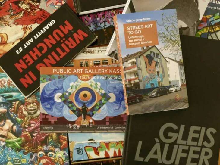 Eine Auswahl an Büchern und Broschüren über Street-Art und Graffiti, die auf einem Tisch ausgebreitet sind, darunter Titel wie "Street-Art to go" und "Writing in München". Wieder mal ein Grund ins Museum zu gehen: Die Kasseler Museums Nacht 2024 - Guided Tour Street‐Art | (c) Kolorcubes