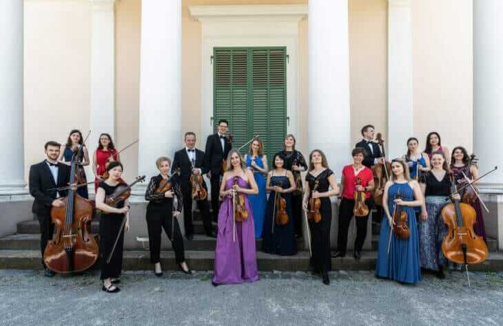 Das Kammerorchester Louis Spohr posiert in eleganter Kleidung mit ihren Streichinstrumenten vor einem historischen Gebäude. Kammerorchester Louis Spohr sind bereit für die Kasseler Musiktage 2024 | (c) Mischa Blank
