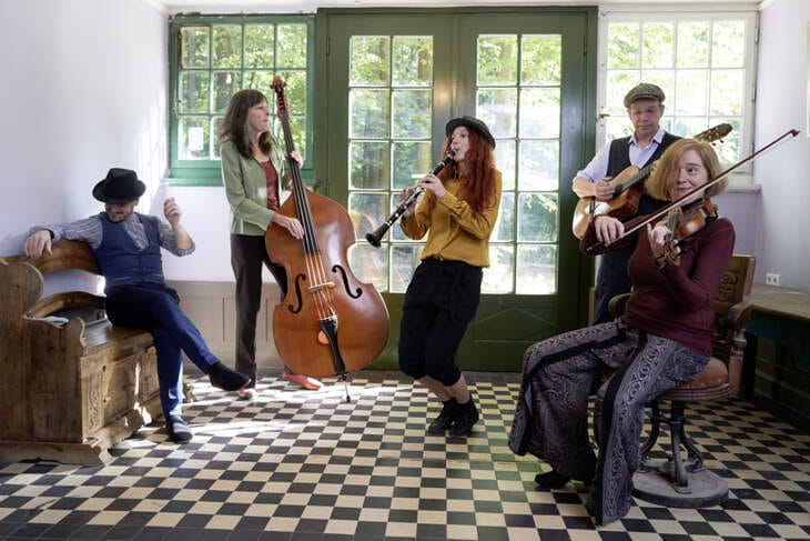 Die Klezmer-Band Mischpoke musiziert in einem hellen Raum mit großen Fenstern; die Musiker spielen Klarinette, Kontrabass, Geige und Gitarre. Klezmer-Zauber live in Kassel: Mischpoke live in der Kreuzkirche