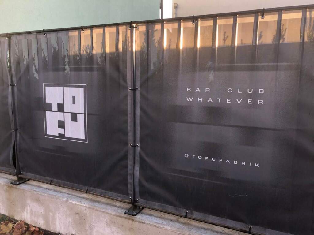 Zaunbanner der Tofufabrik mit Logo und Slogan