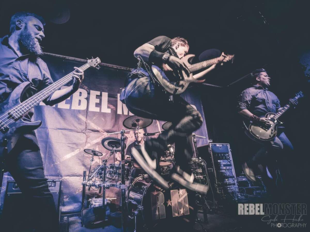 Rebel Monster Band live auf der Bühne mit energiegeladenem Gitarrensprung Rebel Monster | (c) Gabi Henke
