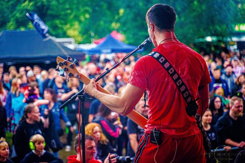 Bassist spielt live auf Festivalbühne vor einer Menschenmenge, Rock For Tolerance Da das zweite Konzert des Rock For Tolerance 2025 auf den längsten Tag des Jahres, den 21. Juni, fällt, erwartet die Fans eine lange Rocknacht. | (c) Sebastian Heise