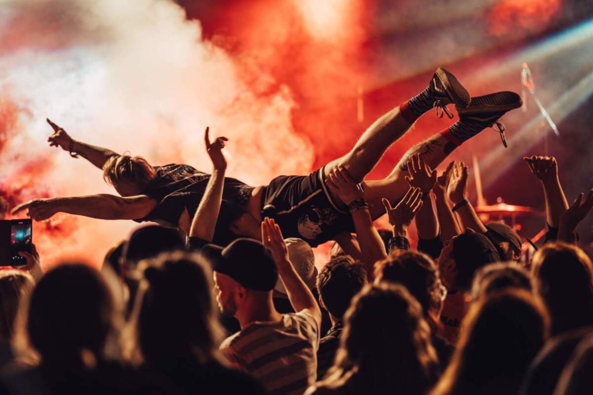 Ein Besucher surft über die Menge beim Keine-Panik-Festival 2024 – Festivalfeeling pur vor rot-orangem Bühnenlicht. Volle Energie beim Keine-Panik-Festival 2024 – mit neuem Bierpartner wartet 2025 auf den nächsten Höhenflug.