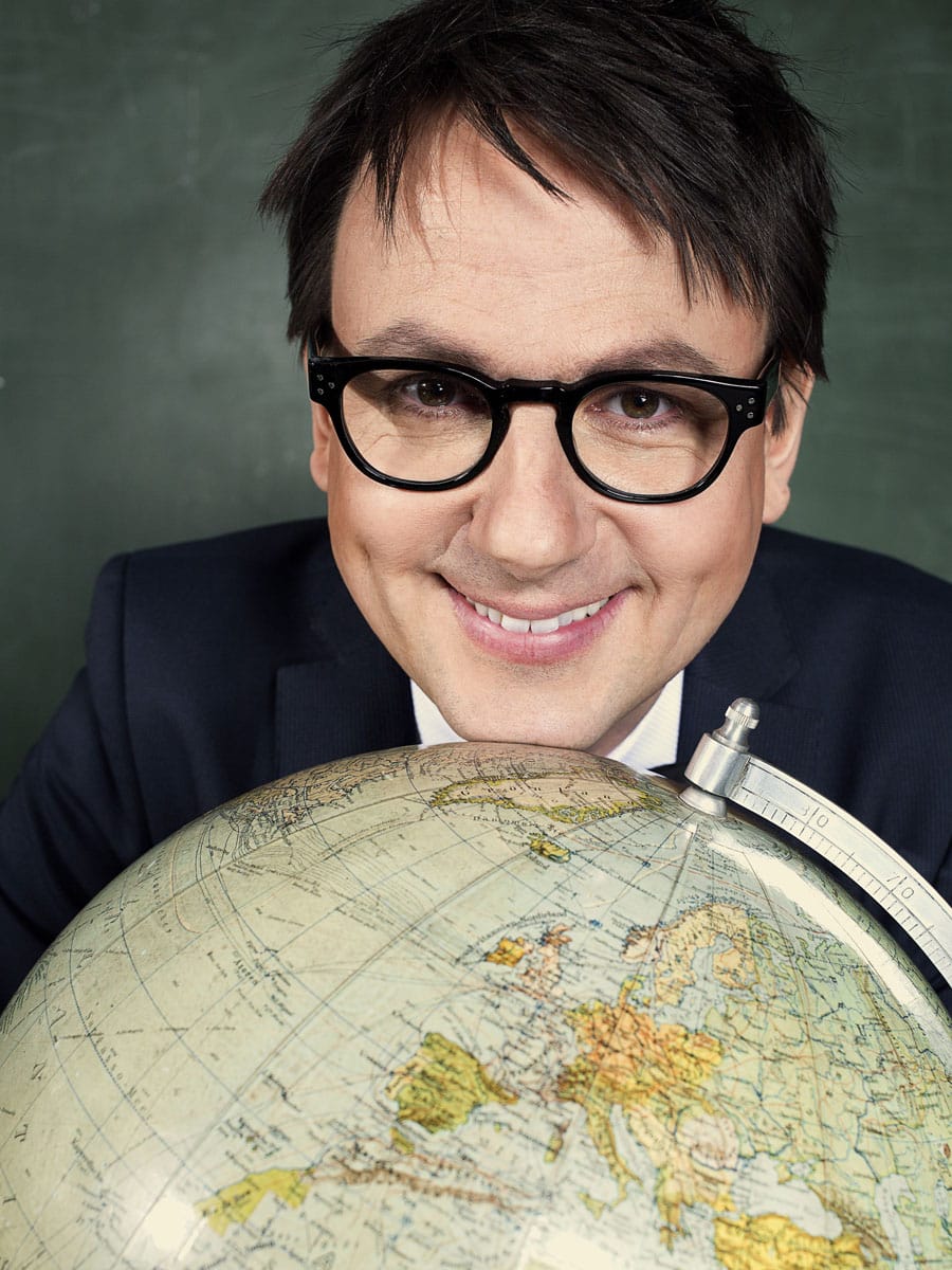 Sebastian Schnoy schaut verschmitzt hinter einem Globus hervor. Er lächelt in die Kamera und trägt eine markante, schwarze Briille. Sebastian Schnoy kommt zur Literatura mit: Europa hoch | (c) Franca Wrage
Sebastian Schnoy kommt zur Literatura mit »Die Vereinigten Träume von Europa« | (c) Franca Wrage