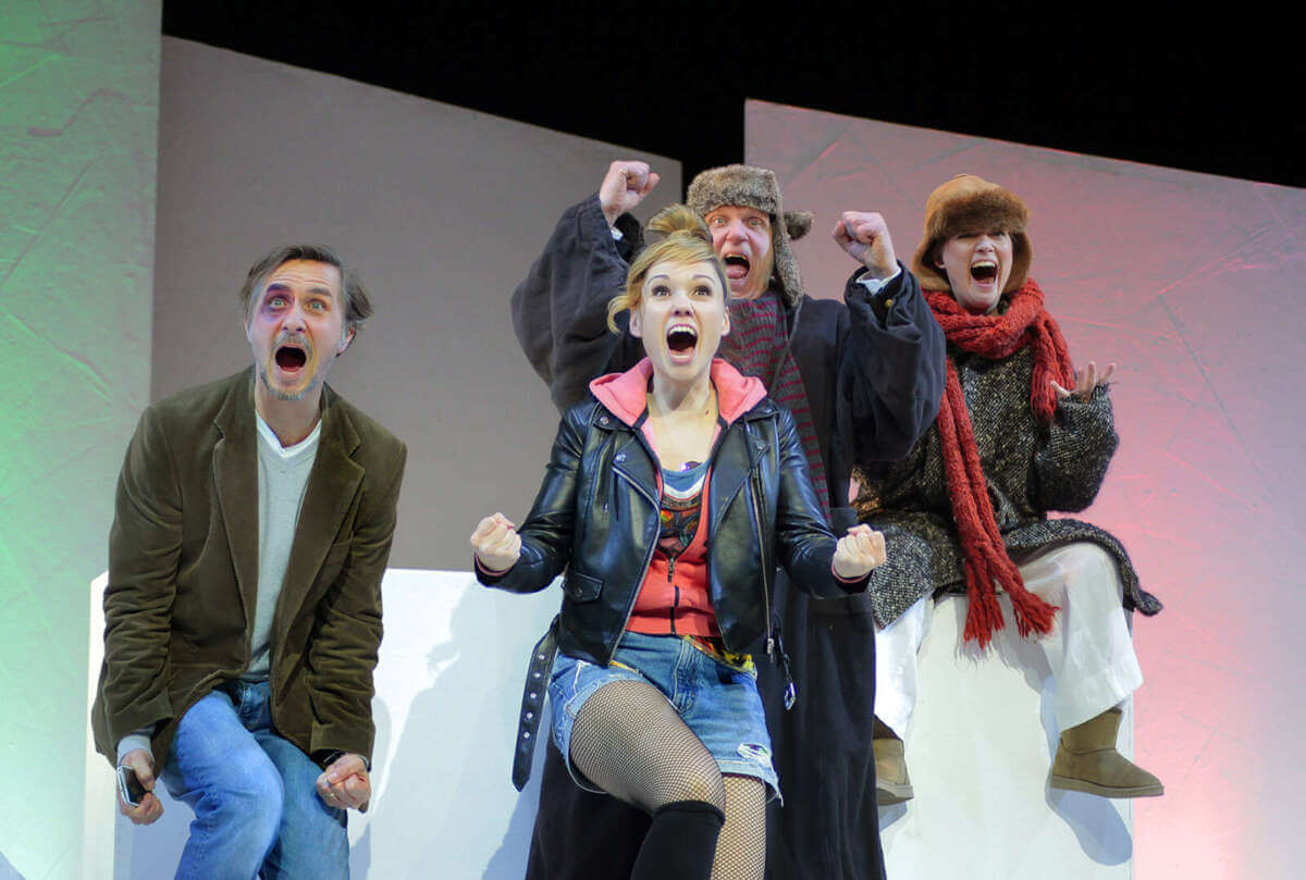 Vier Schauspieler reagieren mit begeisterten Gesten und geöffneten Mündern in einer Szene aus „Der erste letzte Tag“. | (c) Dietrich-Dettmann
