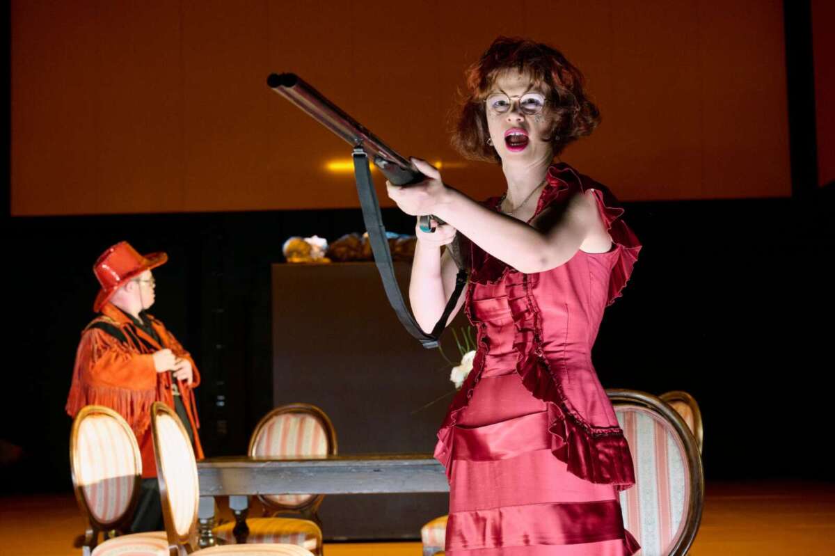 Schauspielerin zielt mit Gewehr in rotem Bühnenkostüm Tango | ein inklusiver Spaß rund um die Freiheit von Sławomir Mrożek | Eva Fuchs, Helge Ahrens (c) Katrin Ribbe 462