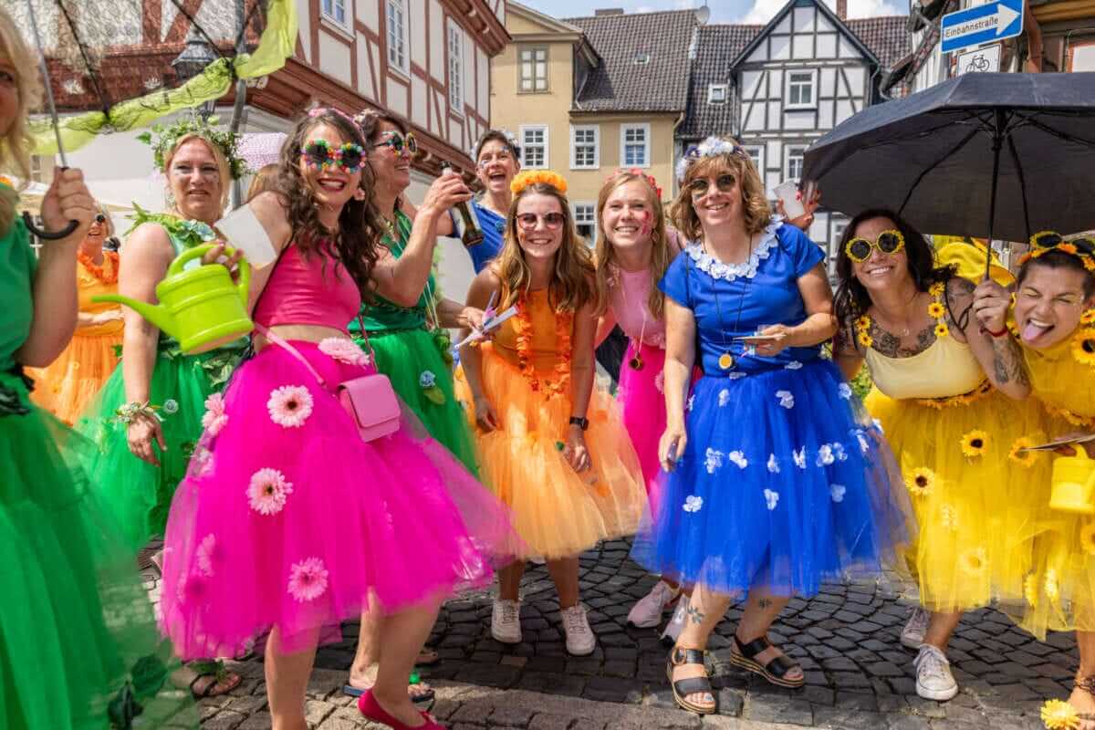 Gruppe Frauen in bunten Kleidern und Blumen beim Straßenfest Gute Stimmung scheint garantiert zu sein beim Wolfhager Kram- und Viehmarkt 2025 | (c) Stadt Wolfhagen