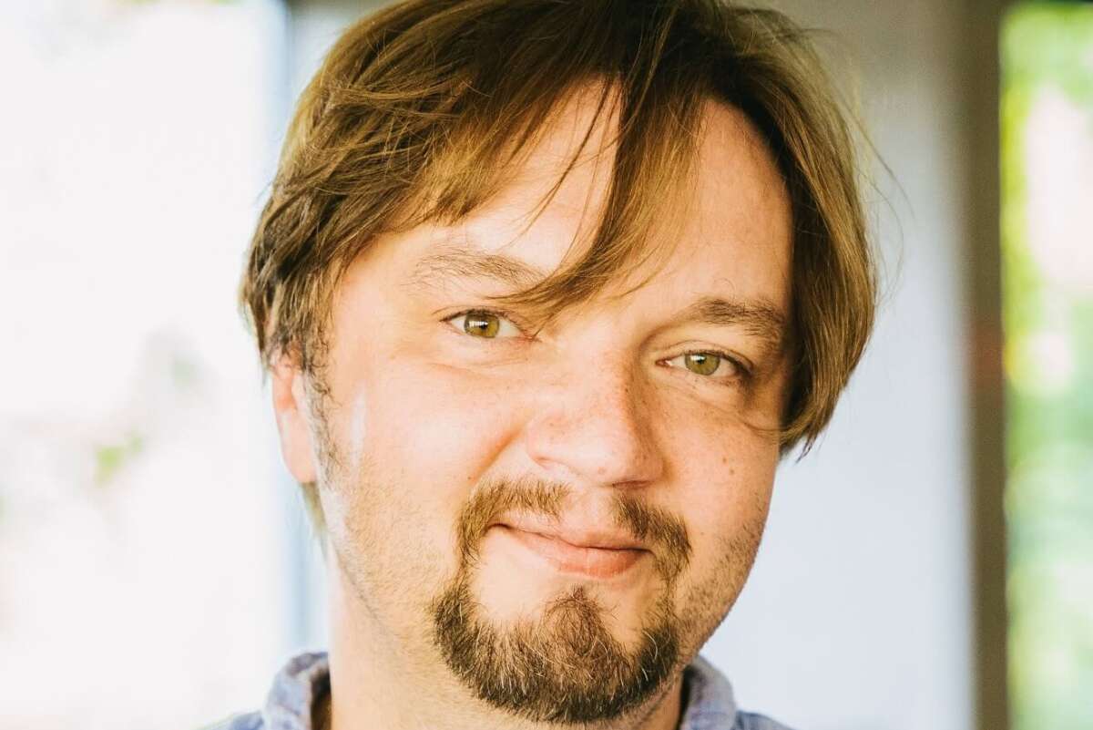 Auf dem Foto ist Ainars Rubikis, der GMD (Generalmusikdirektor), in seiner Funktion als Leitung für „Le nozze di Figaro“ am Staatstheater Kassel zu sehen. Er hat braune Haare und braune Augen. Sein Gesichtsausdruck ist freundlich, er lächelt leicht. Er trägt ein Hemd. Der Hintergrund des Bildes ist hell, ohne erkennbare Details oder Ablenkungen, sodass die Aufmerksamkeit auf ihm liegt. Das Bild wirkt professionell und freundlich zugleich. GMD Ainars Rubikis als Leitung für »Le nozze di Figaro« im Staatstheater Kassel | (c) Sylwester Pawliczek