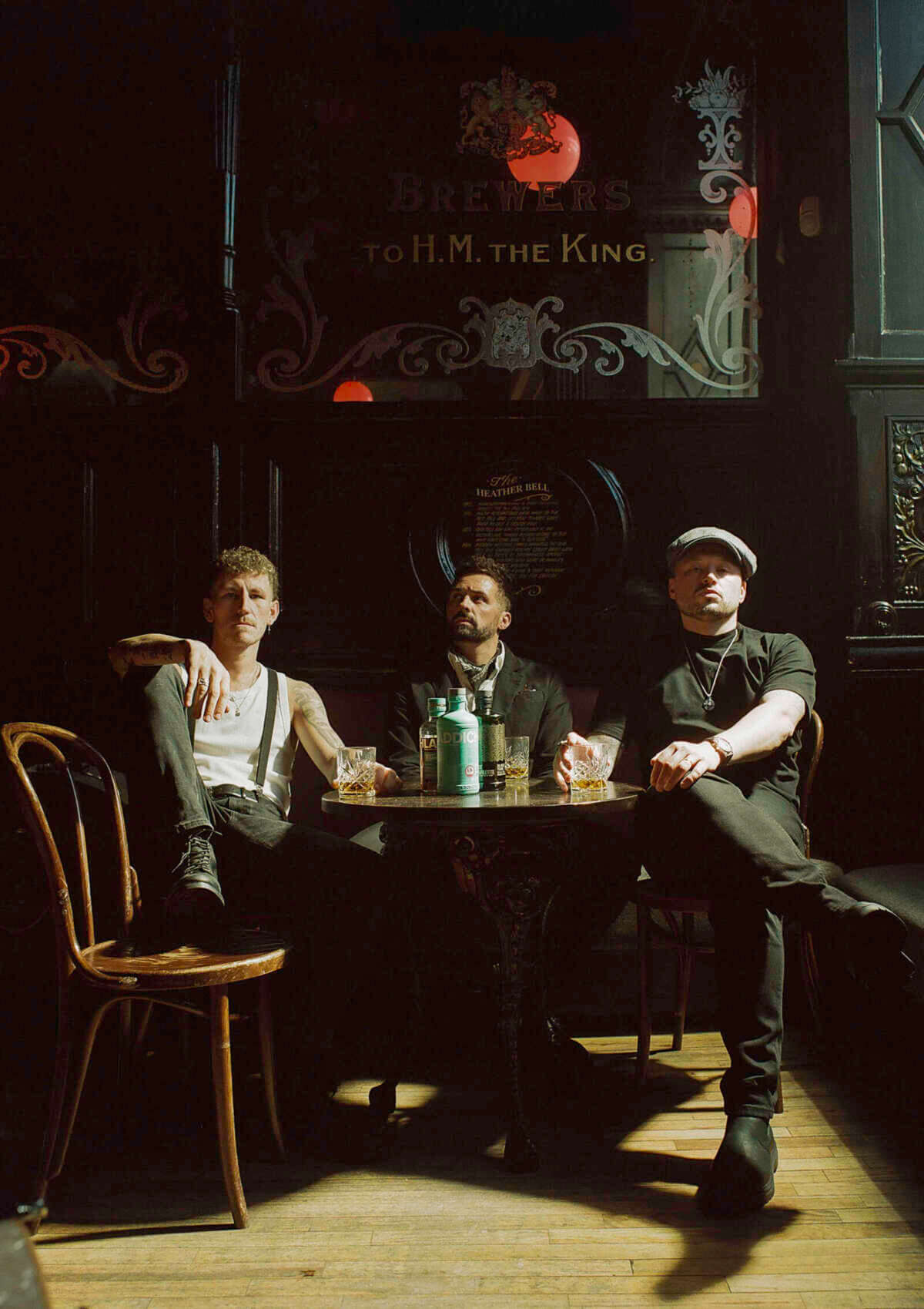 Nathan Evans mit Band in einem dunklen Pub, Whiskeygläser auf dem Tisch, Stimmung zwischen Folk und Seemannslied – Auftritt beim Kulturzelt Kassel 2026. Noch sitzt Nathan Evans mit Bandkollegen im Pub – Aber bald live im Kulturzelt Kassel | (c) Nathan Evans