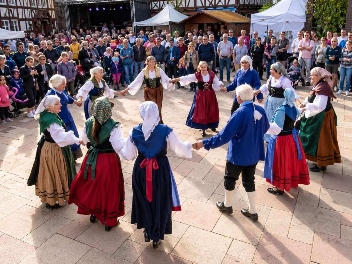 Traditioneller Tanz beim Dornröschenfest Hofgeismar: In historischen Trachten führen Tänzerinnen und Tänzer einen Reigen auf und bringen gelebtes Brauchtum mitten in die Altstadt – umringt von begeisterten Besuchern.  Dornröschenfest Hofgeismar - KI generiert - (c) Wildwechsel