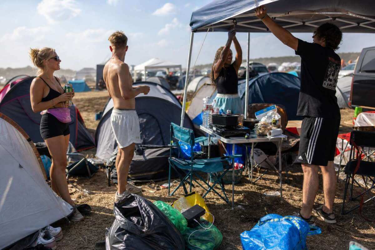 Festival Camping Szene mit Pavillon, Zelten, Gaskocher, Wasserflaschen und Campingausrüstung auf einem Festivalplatz