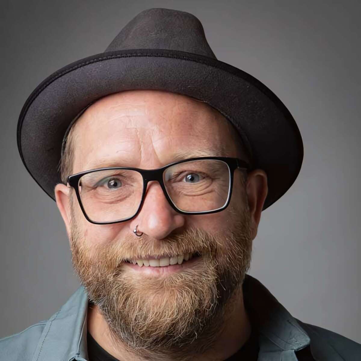 Das Bild zeigt Gregor Meyle als nahes Porträt. Er trägt einen dunklen Hut, eine schwarze Brille und Bart und lächelt freundlich in die Kamera. Gregor Meyle ist beim Butzbach Open Air 2026 dabei und lächelt auf einem Porträt mit Hut und Brille. | (c) Ralf Schönenberg