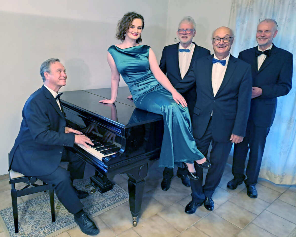 Sängerin des Marilyn Monroe Quintetts sitzt auf einem Flügel, umgeben von den Musikern des Ensembles vor dem Auftritt am 1. Juni im Theaterstübchen Kassel.