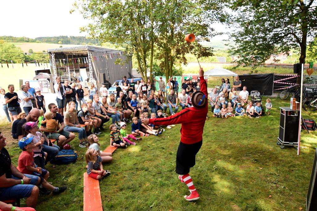 Straßenkünstler begeistert Kinder und Erwachsene beim Familienprogramm des Kraut & Rüben Musikfestivals in Hembsen vor der Open-Air-Bühne. | (c) Ela Rüther