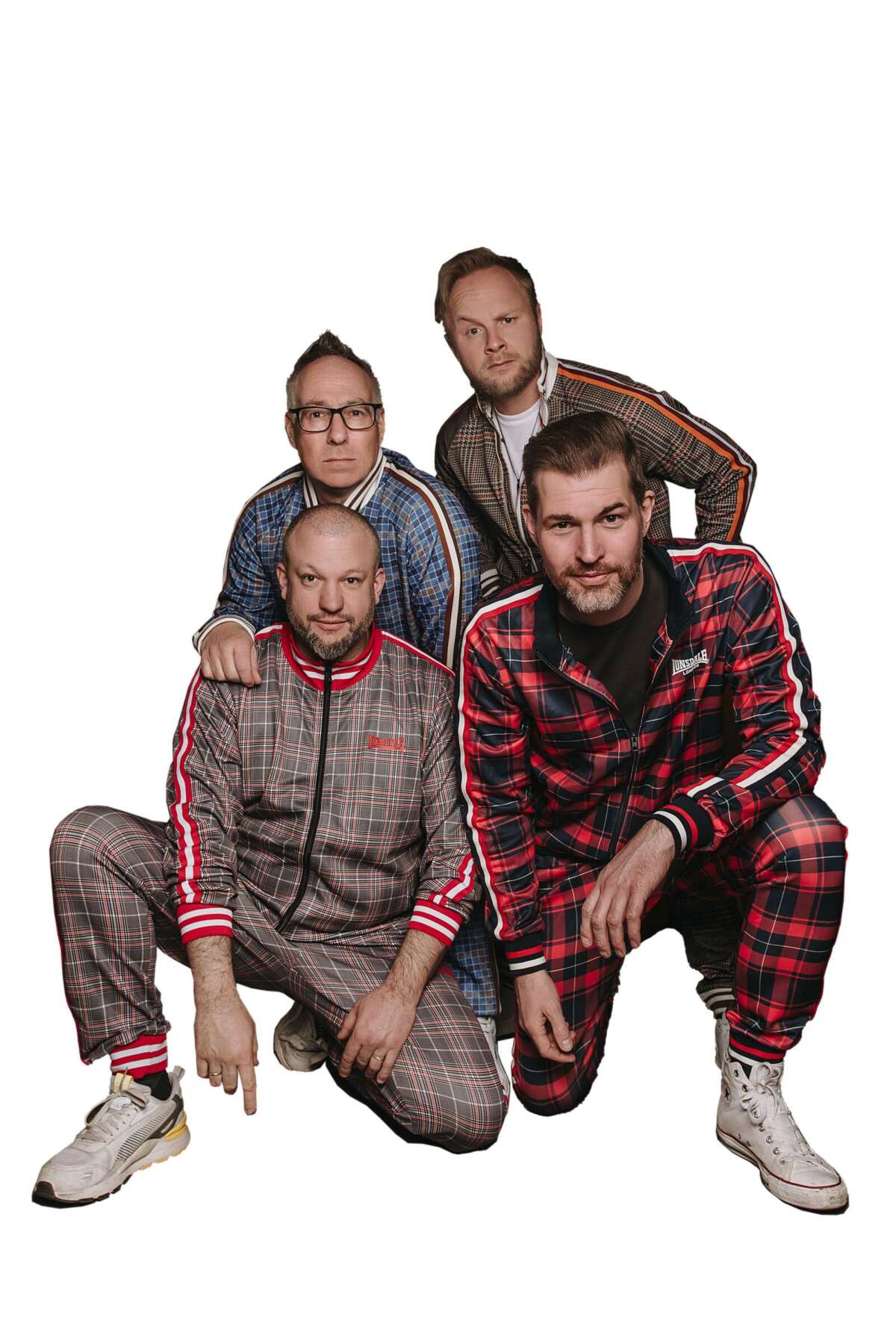 Vierköpfige Band in auffälligen karierten Trainingsanzügen bei einem Gruppenfoto.