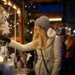 Besucherin betrachtet Weihnachtsdekoration an einem beleuchteten Kunsthandwerksstand in Bad Arolsen