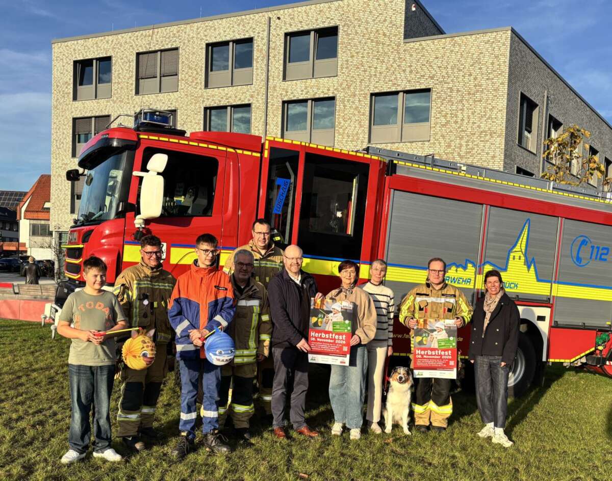Organisationsteam des Delbrücker Martinsumzugs mit Laternen und Herbstfest-Plakaten vor einem Feuerwehrfahrzeug