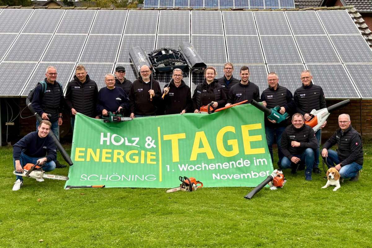 Organisationsteam der Schöninger Holz- und Energietage mit Werkzeugen und Veranstaltungsbanner vor Solarmodulen
