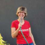 Katrin Iskam hält lachend einen Gartenschlauch – Foto: Nicole Müller