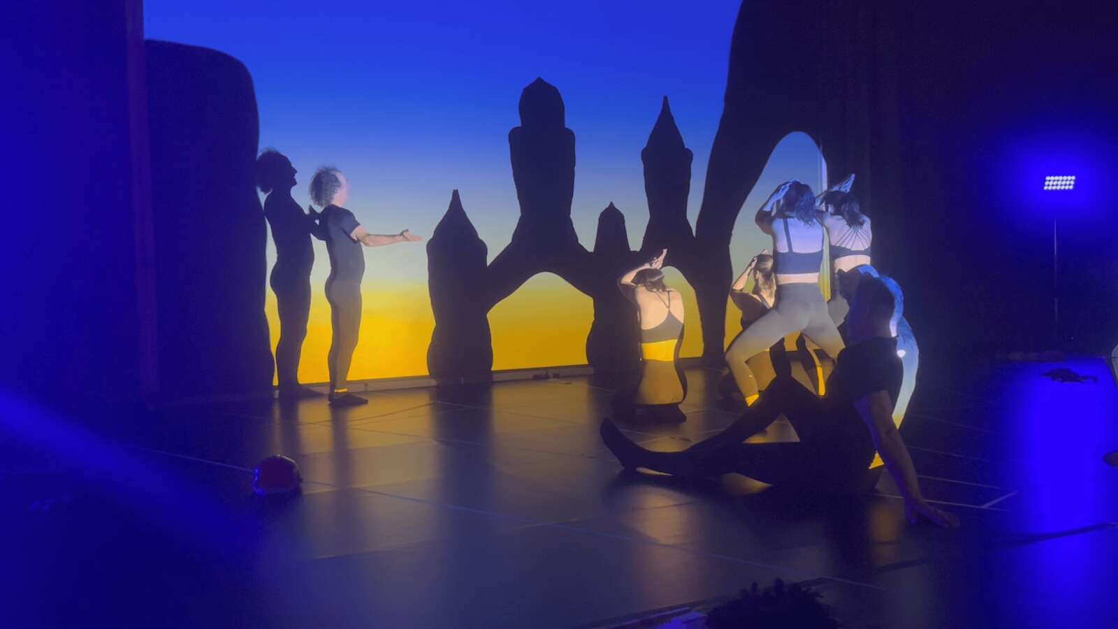 Blick auf die Schattenfiguren und die Darsteller hinter der Leinwand von Moving Shadows