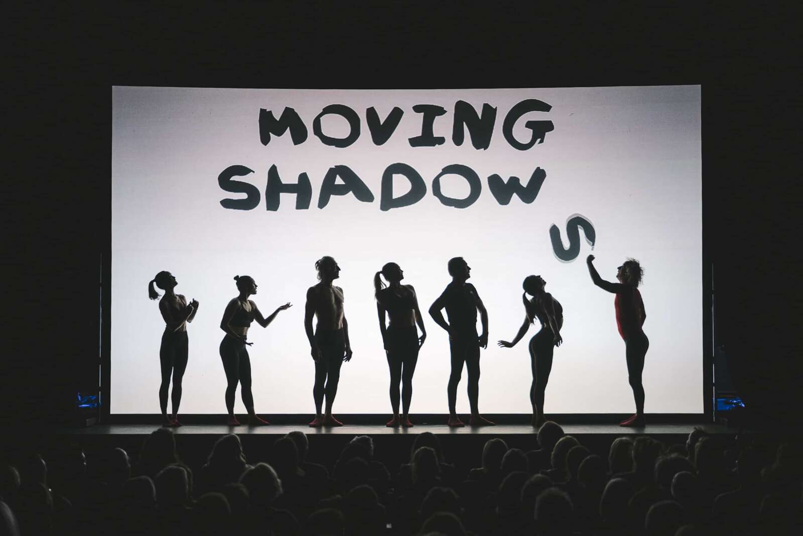 Ensemble von Moving Shadows vor der beleuchteten »On Fire«-Leinwand